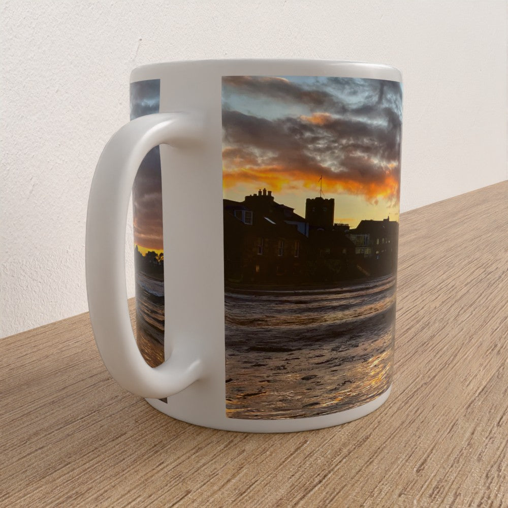 White mug with a scenic sunset design on a wooden surface