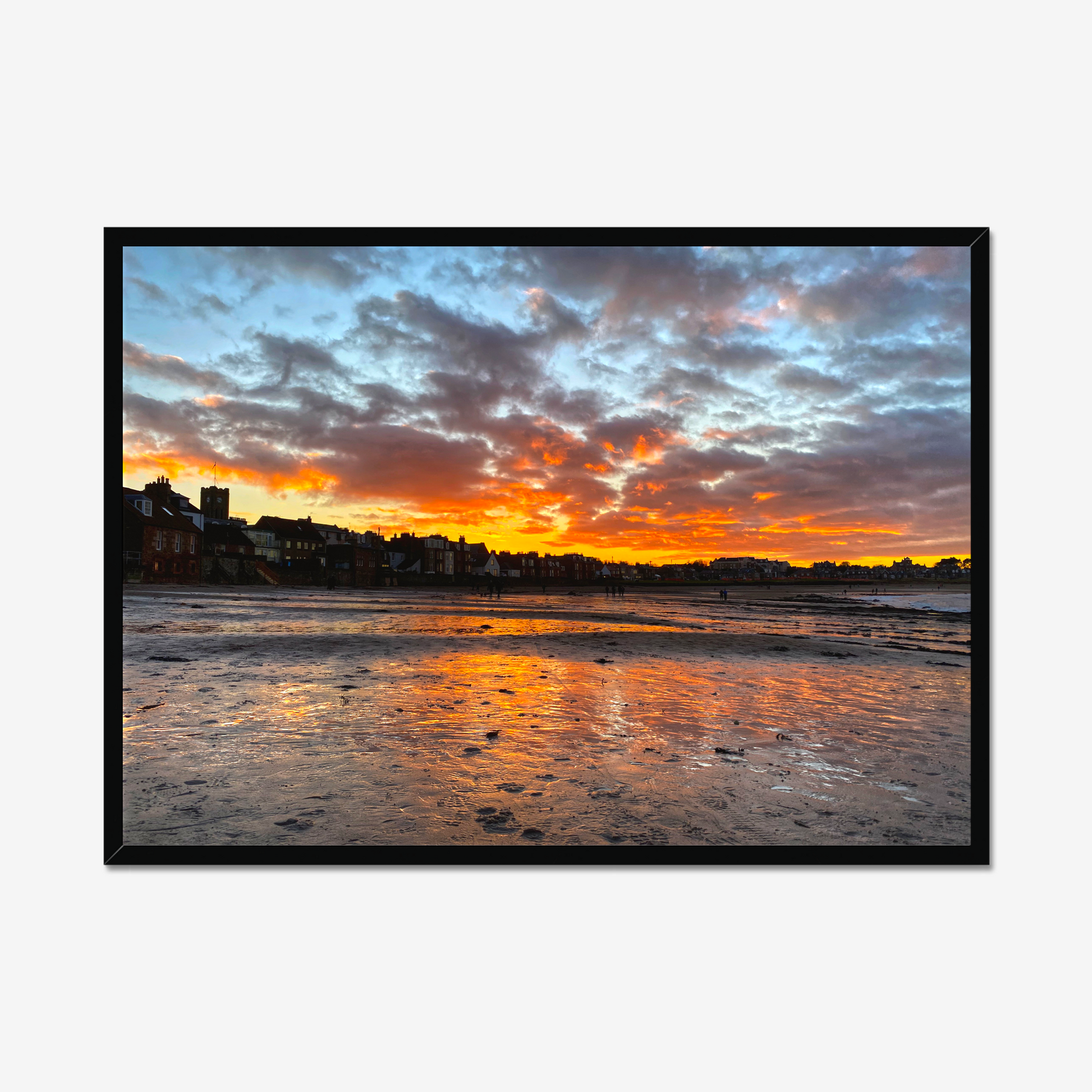Sunset over a coastal town with vibrant colors reflected in the water.