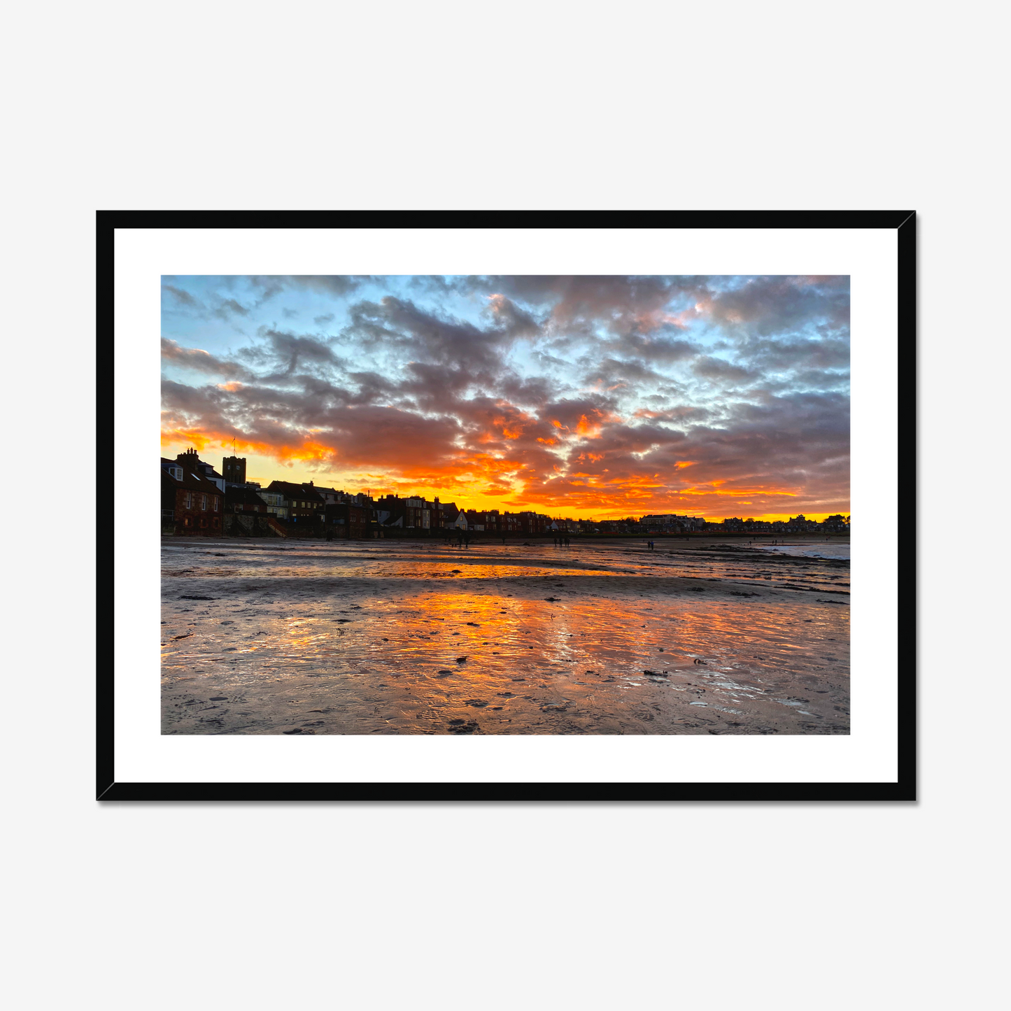 Sunset over a coastal town with vibrant colors reflected in the water.