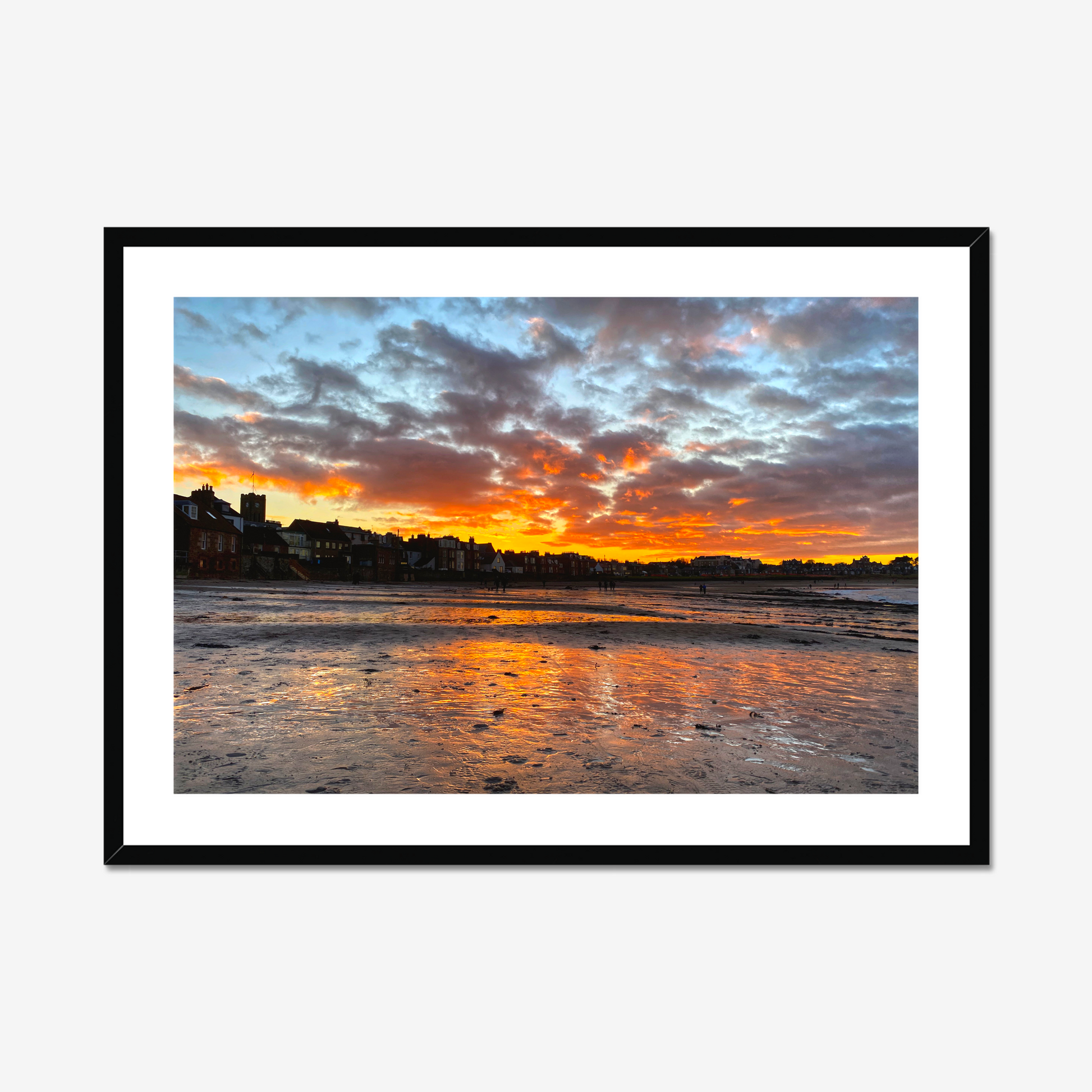 Sunset over a coastal town with vibrant colors reflected in the water.