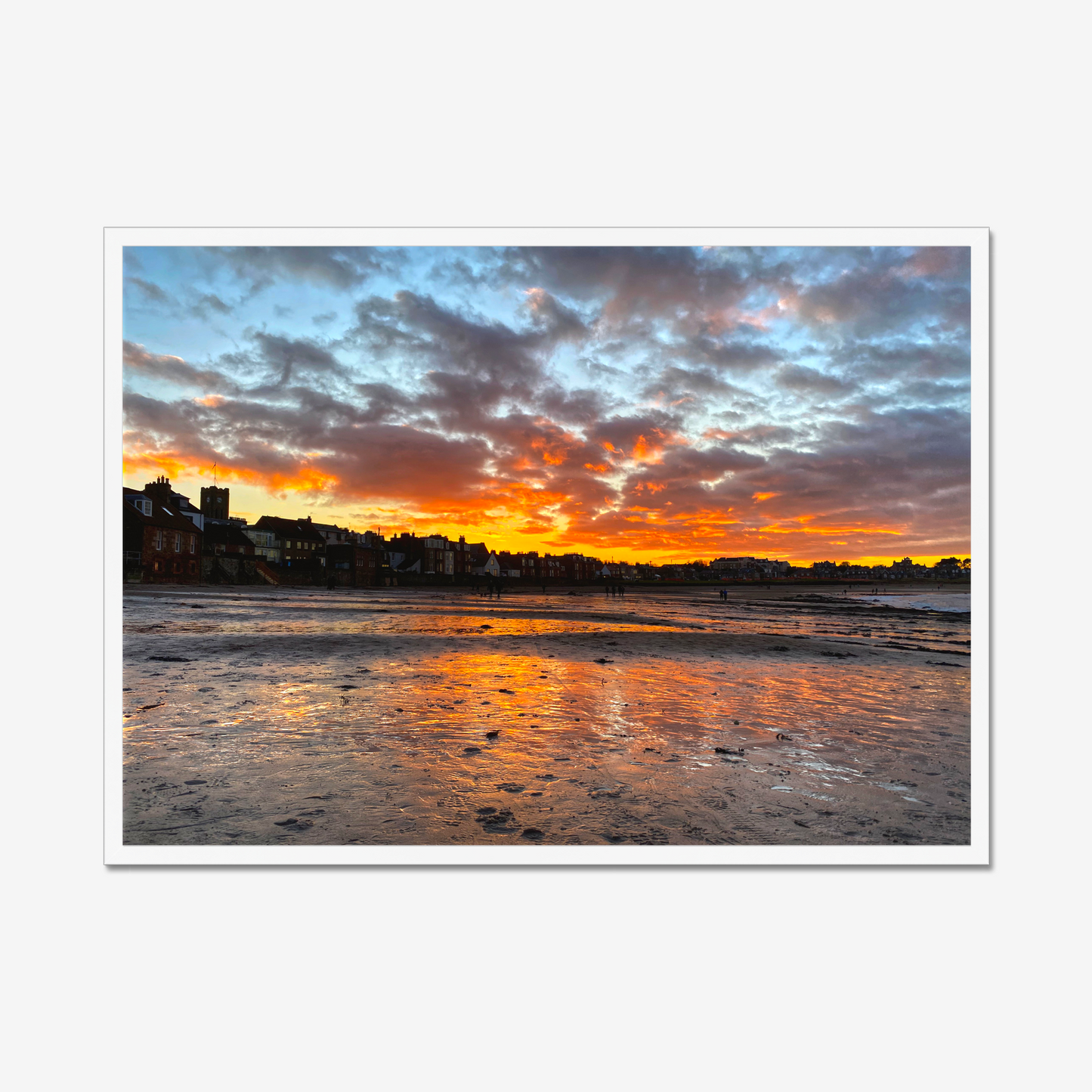 Sunset over a coastal town with vibrant colors reflected in the water.