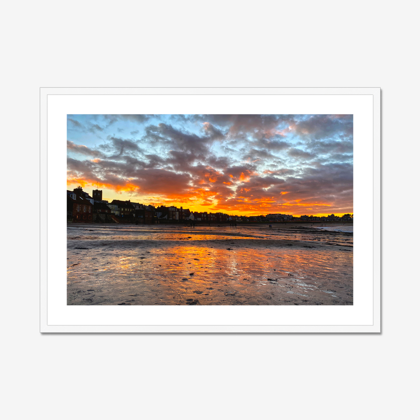 Sunset over a coastal town with vibrant colors reflected in the water.