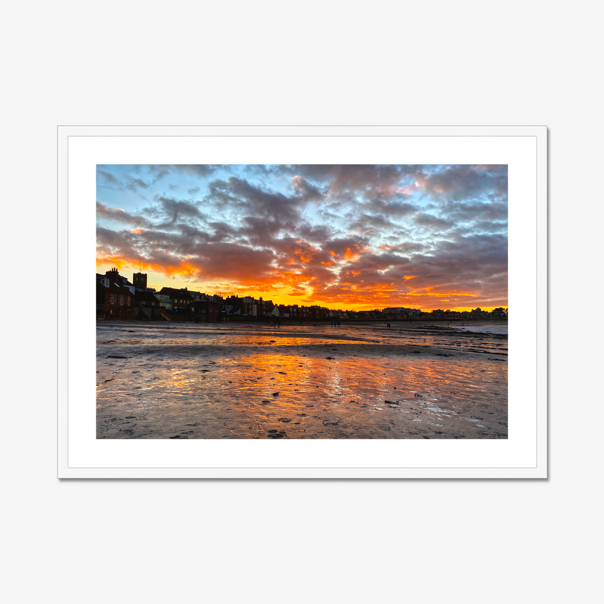 Sunset over a coastal town with vibrant colors reflected in the water.