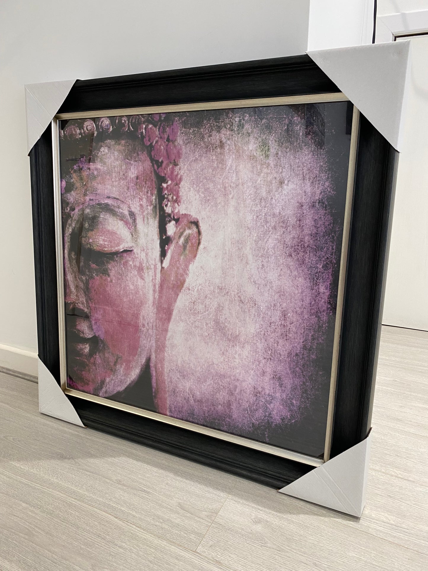 Framed artwork of a face with a purple filter on a wooden surface