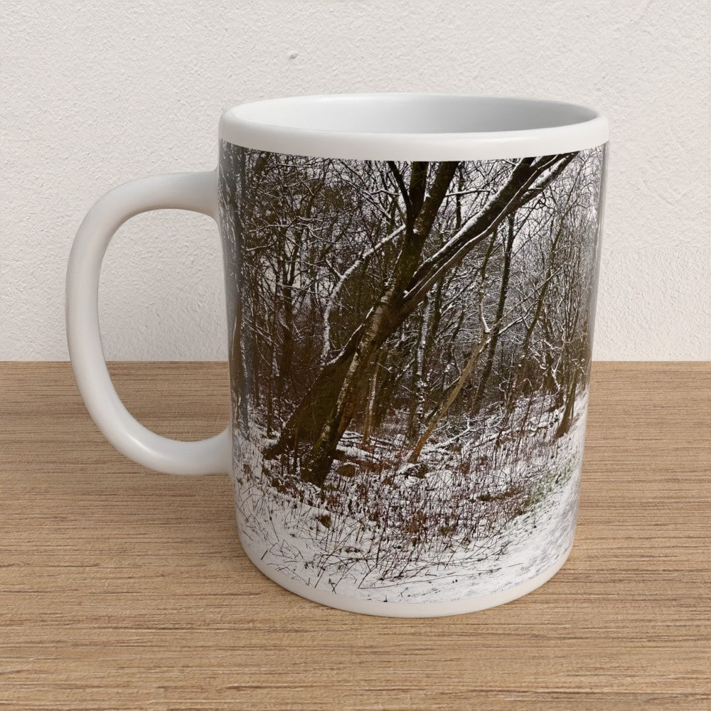 White mug with a winter forest design on a wooden surface