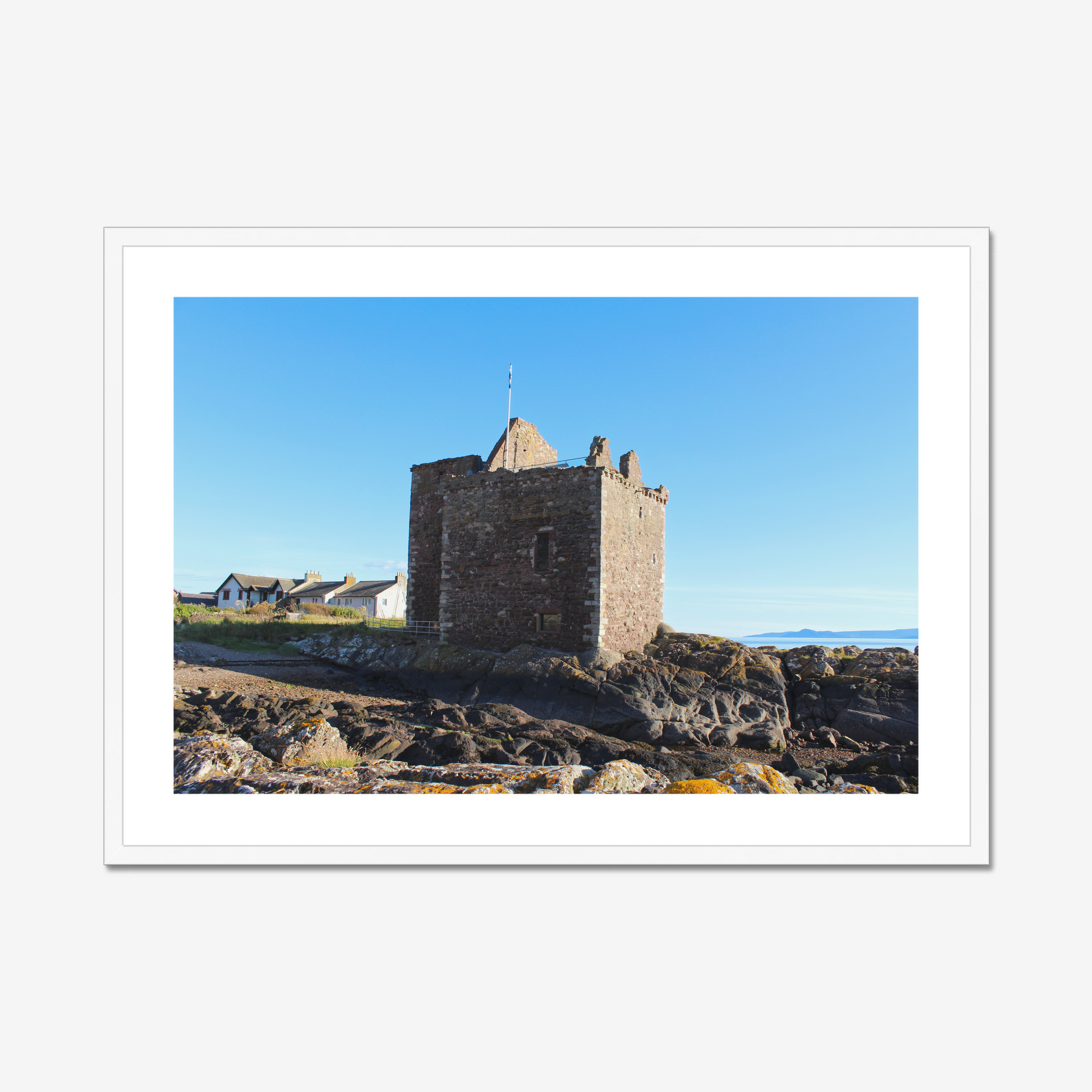 Framed photograph of a stone castle on rocky terrain with a clear blue sky