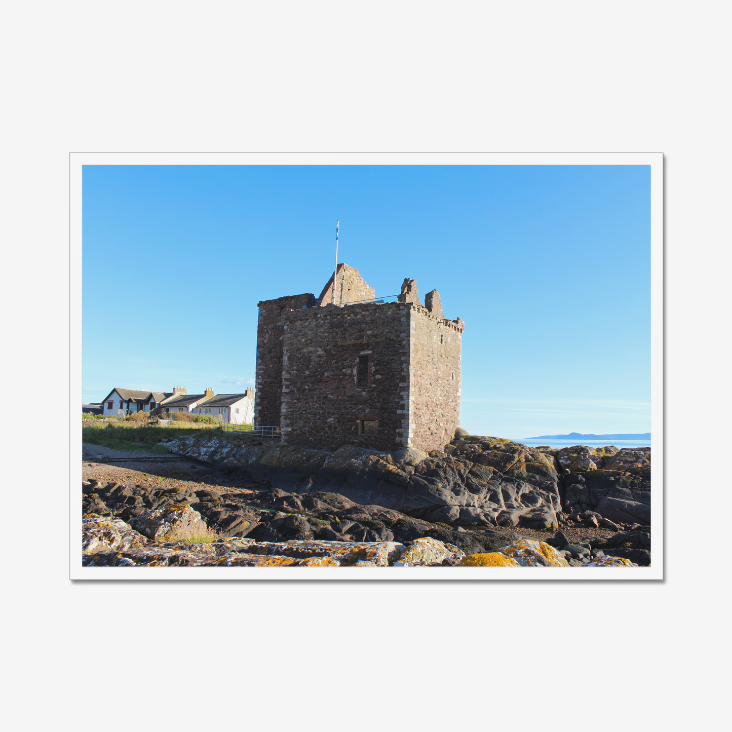 Framed photograph of a stone castle on rocky terrain with a clear blue sky
