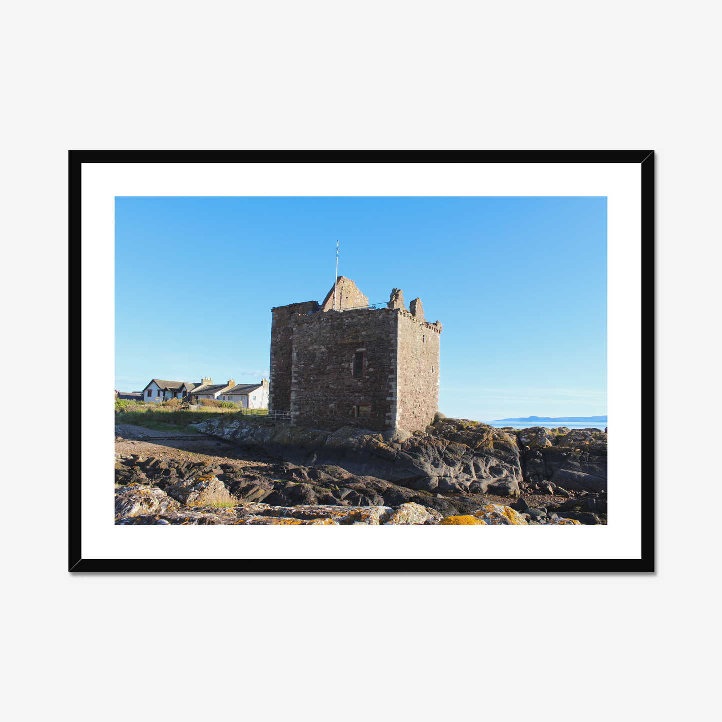 Framed photograph of a stone castle on rocky terrain with a clear blue sky