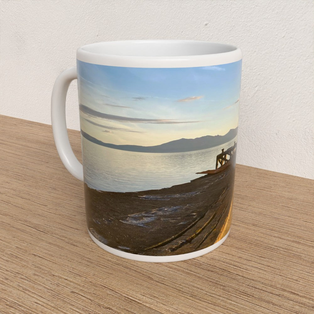 Mug with a scenic design of a lake and mountains on a wooden surface.