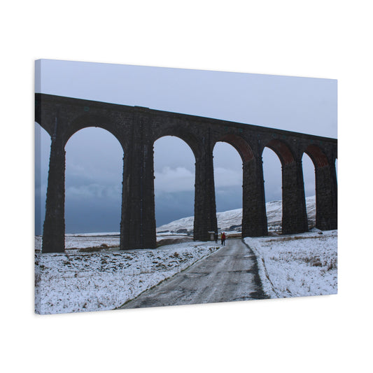 Scenic view of a snow-covered landscape with a large arch bridge.