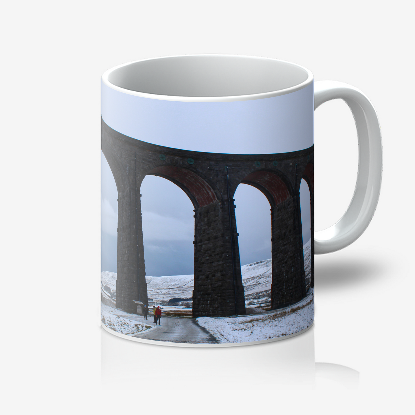 Mug with a design of a snowy landscape featuring a viaduct and people walking on a path.