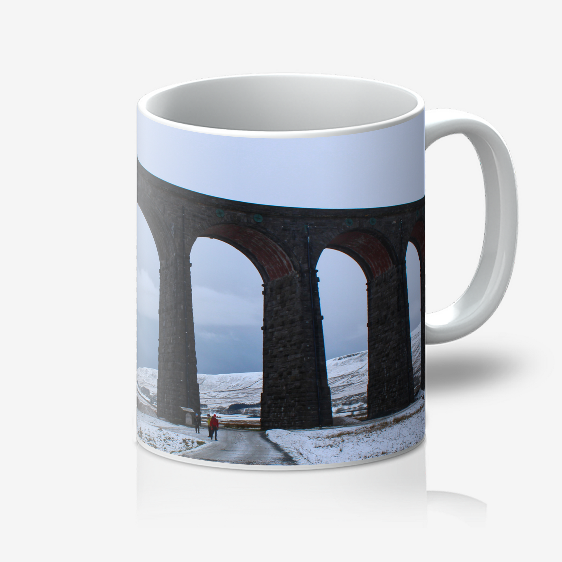 Mug with a design of a snowy landscape featuring a viaduct and people walking on a path.
