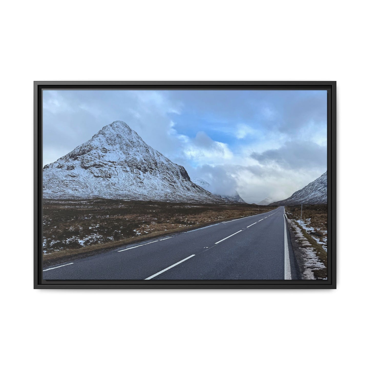 Road leading to a snow-capped mountain under a cloudy sky