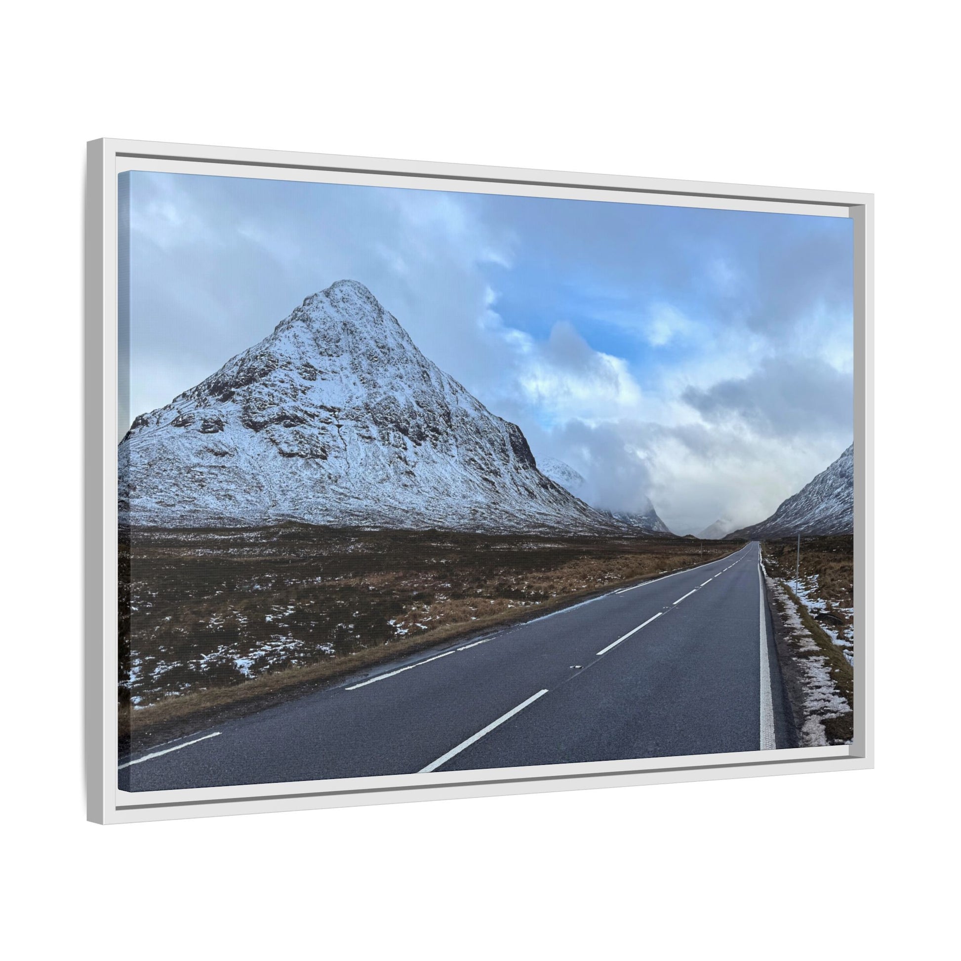 Road leading to a snow-capped mountain under a blue sky with clouds.