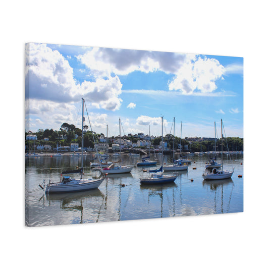 Harbour scene with boats on calm water under a blue sky with clouds