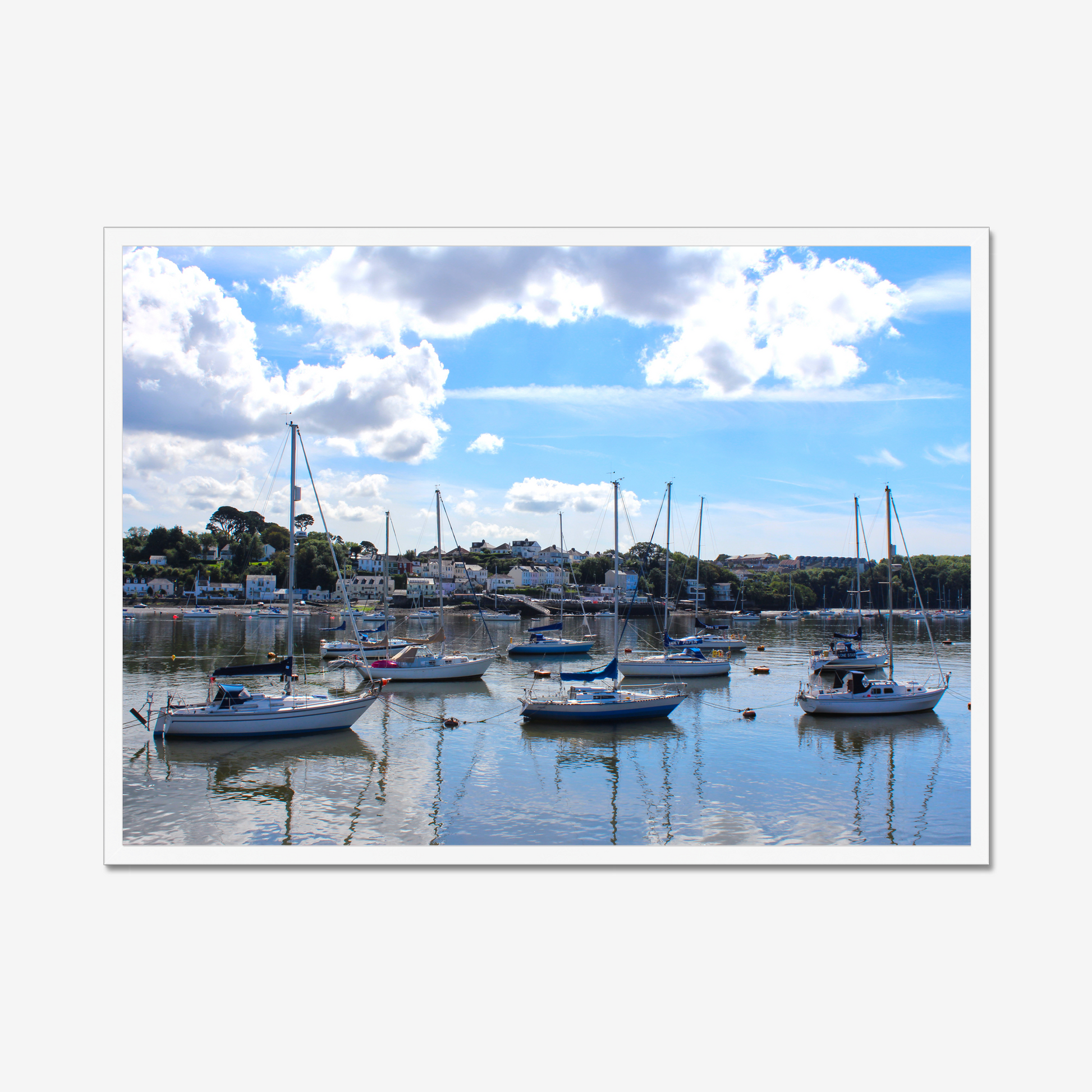 Framed photograph of a harbour scene with boats docked in calm water under a blue sky with clouds.