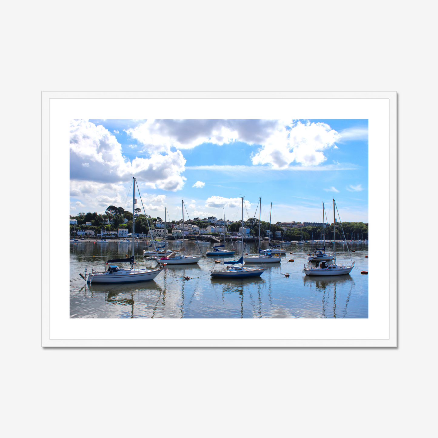 Framed photograph of a harbour scene with boats docked in calm water under a blue sky with clouds.
