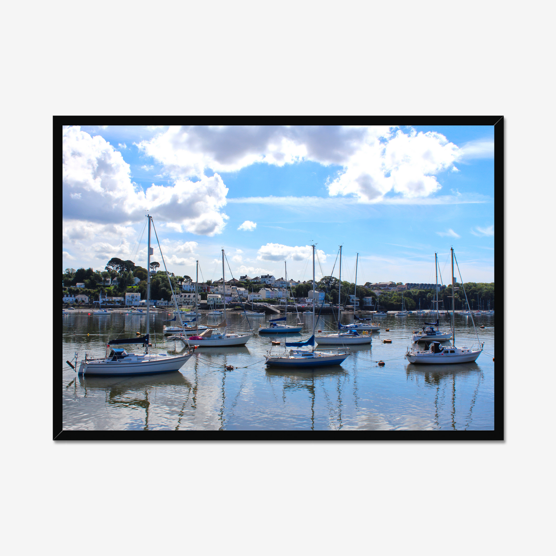 Framed photograph of a harbour scene with boats docked in calm water under a blue sky with clouds.