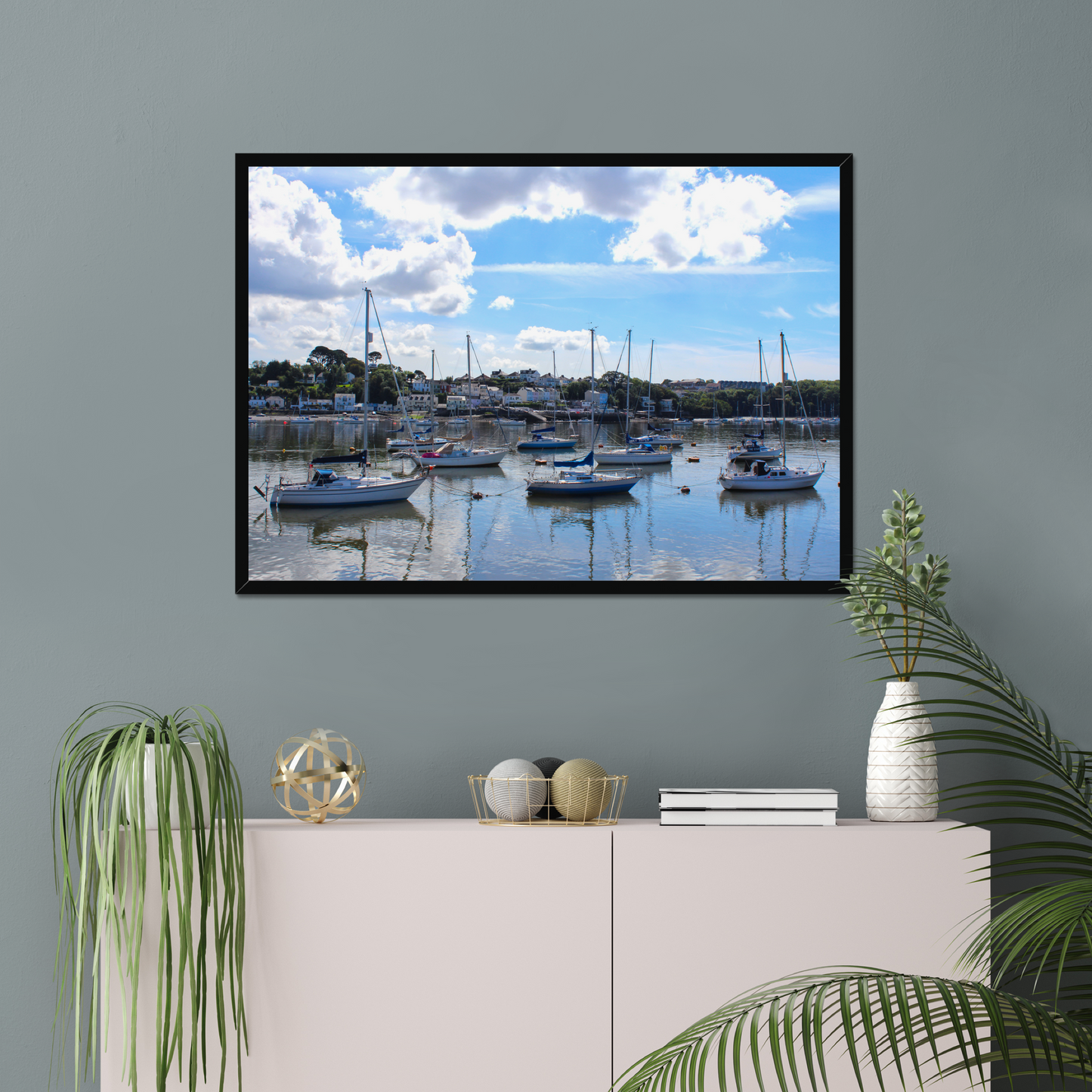 Framed photograph of a harbour scene with boats docked in calm water under a blue sky with clouds.