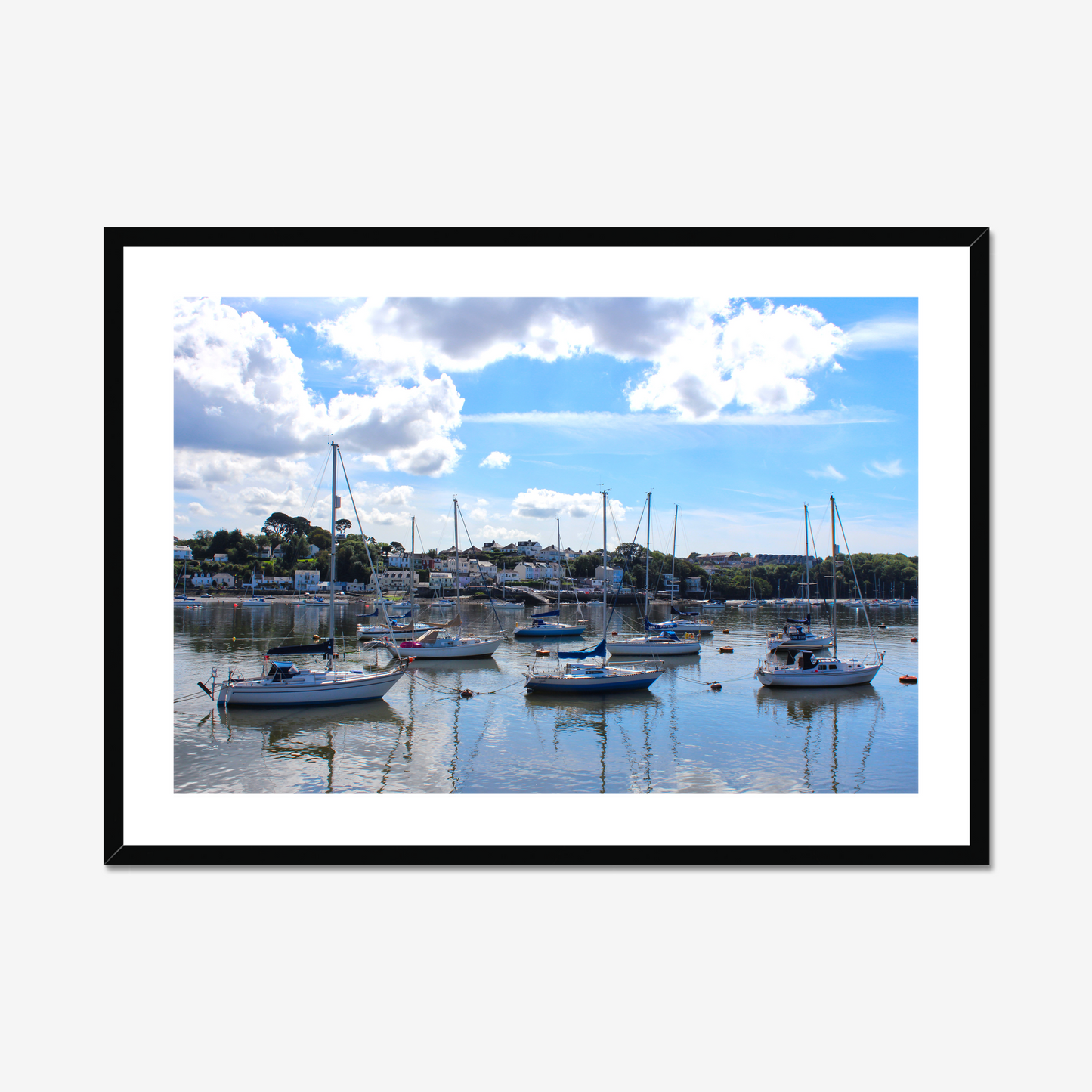 Framed photograph of a harbour scene with boats docked in calm water under a blue sky with clouds.
