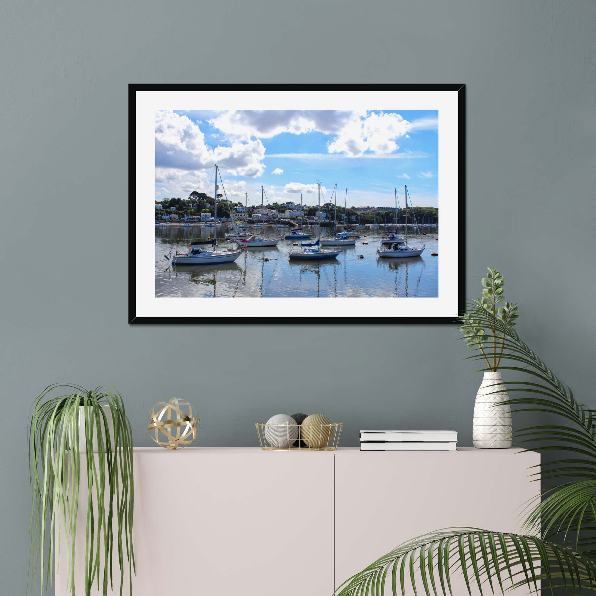 Framed photograph of a harbour scene with boats docked in calm water under a blue sky with clouds.