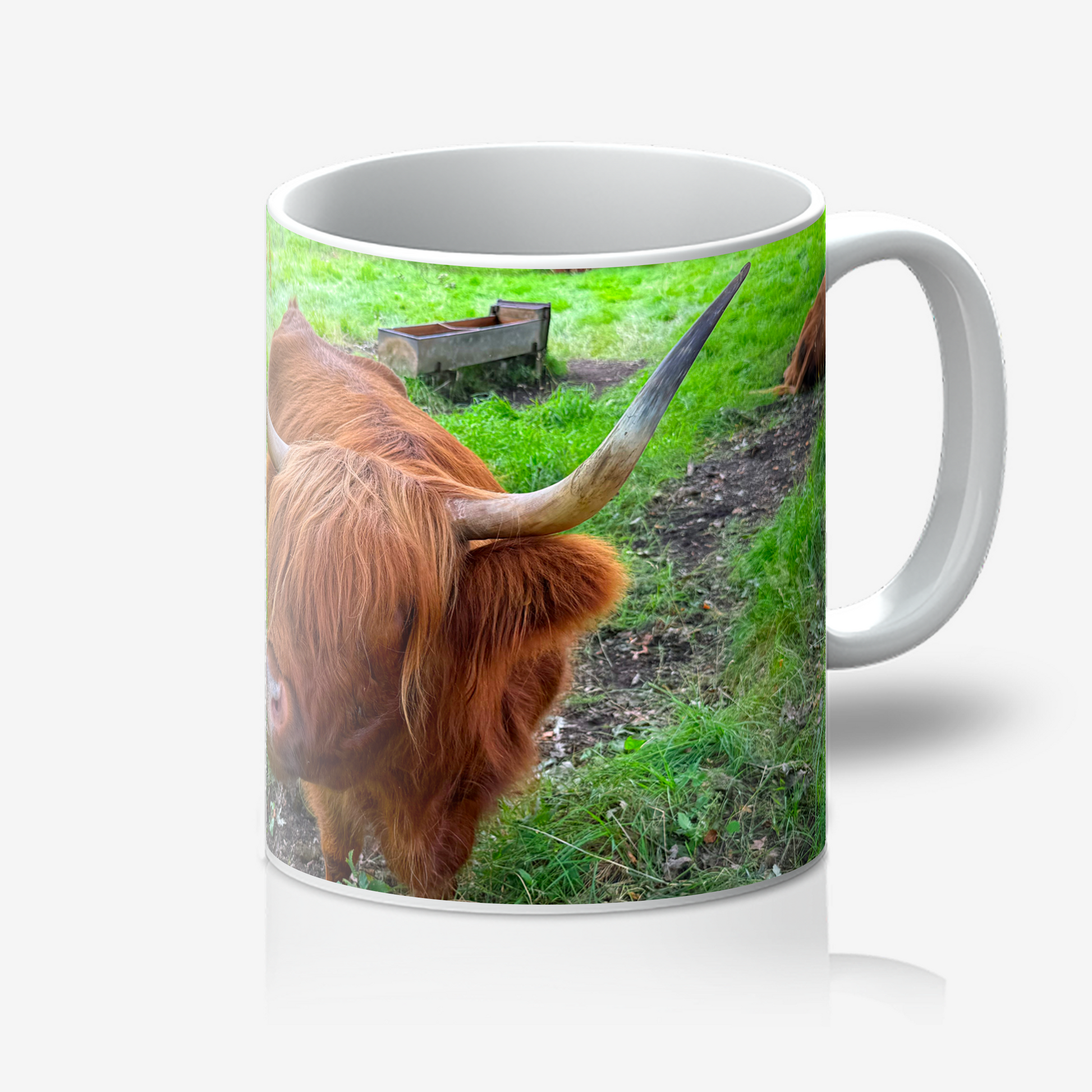 Mug with a design of a highland cow on a grassy field