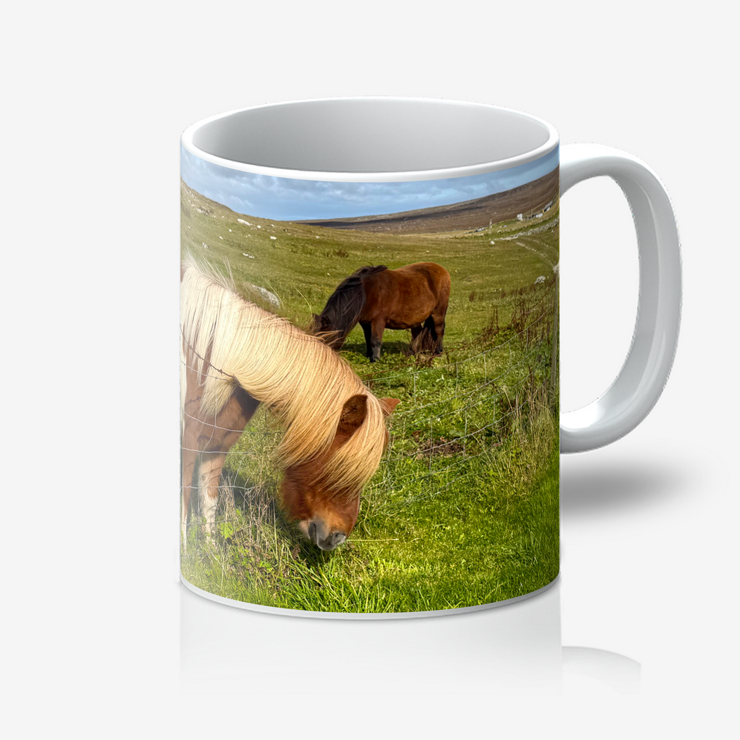 Mug with a design of two horses grazing in a field on a white background