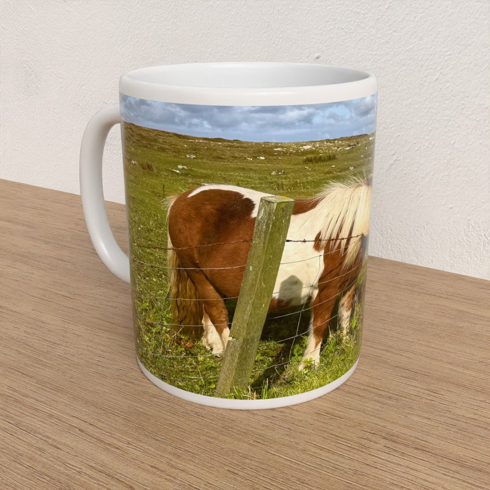 Mug with a horse in a field design on a wooden surface