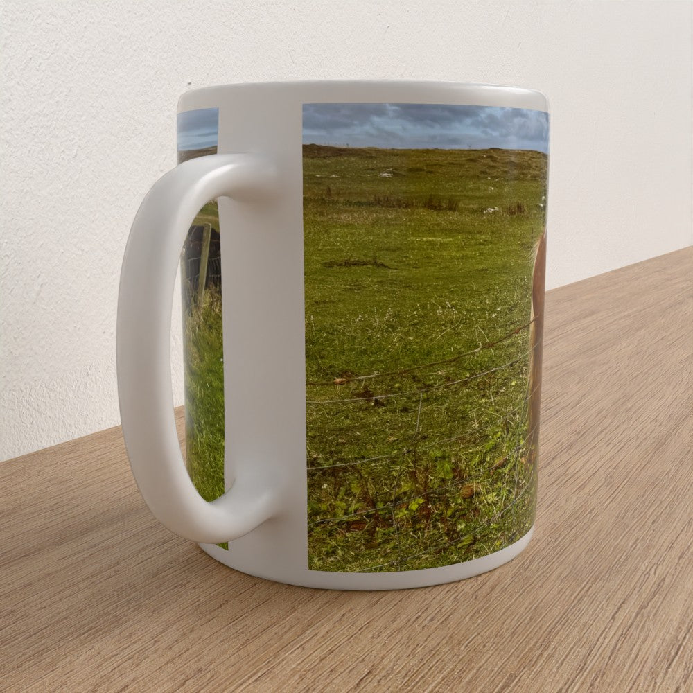 White mug with a scenic print of a grassy field on a wooden surface
