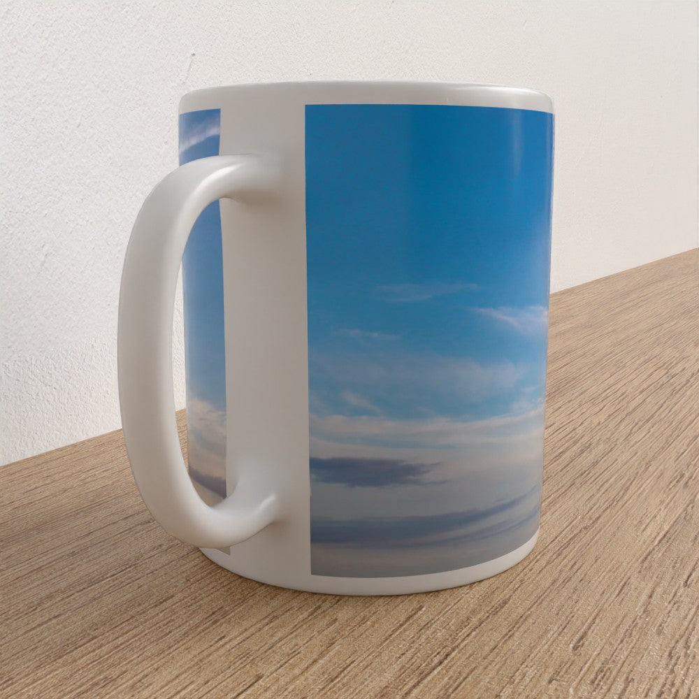 Mug with a blue sky and cloud design on a wooden surface