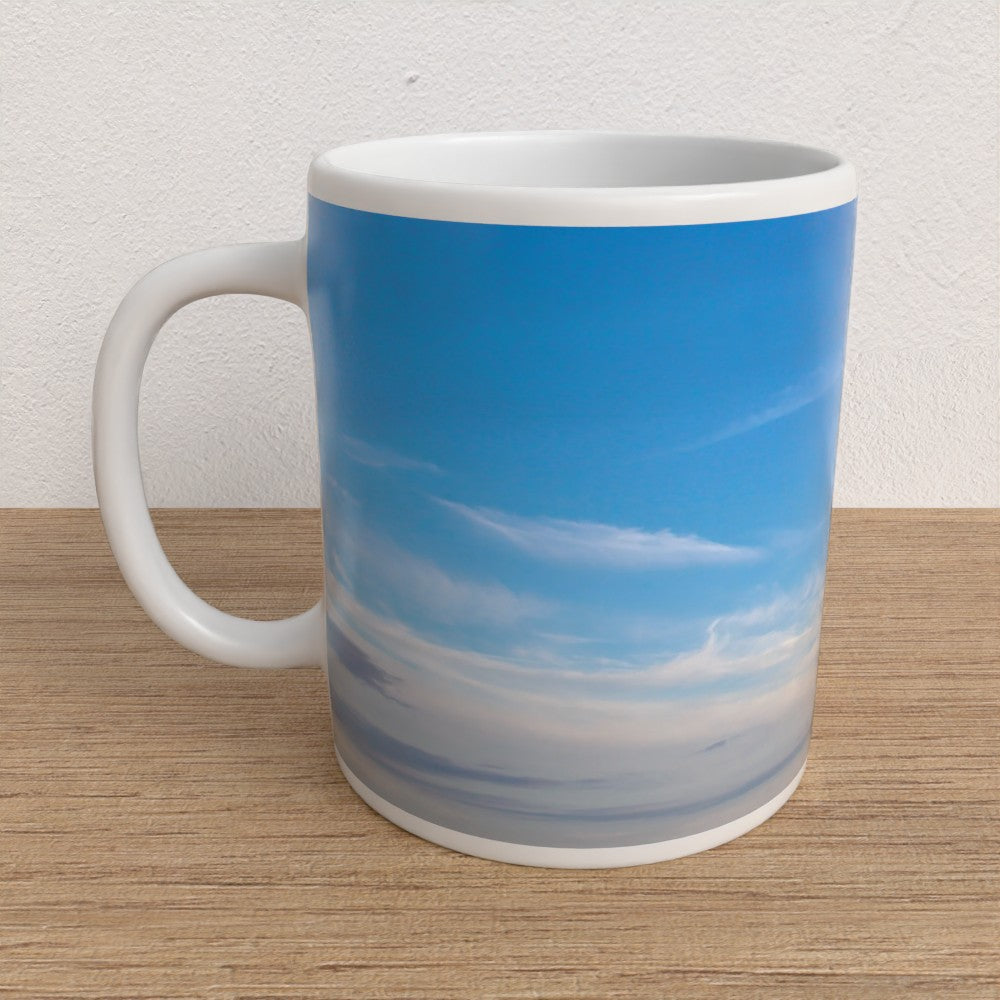 Mug with a blue sky and cloud design on a wooden surface