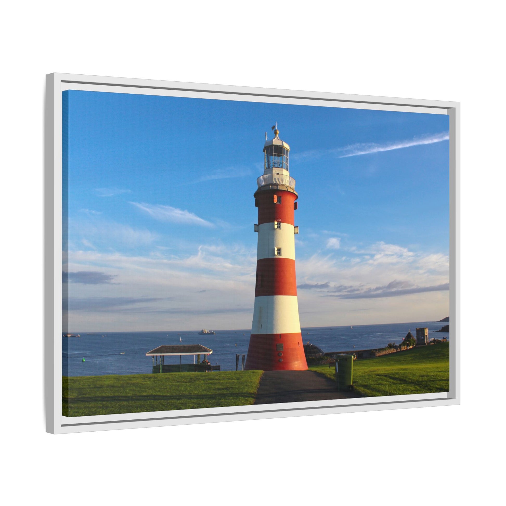 Red and white striped lighthouse on a grassy area with a blue sky.