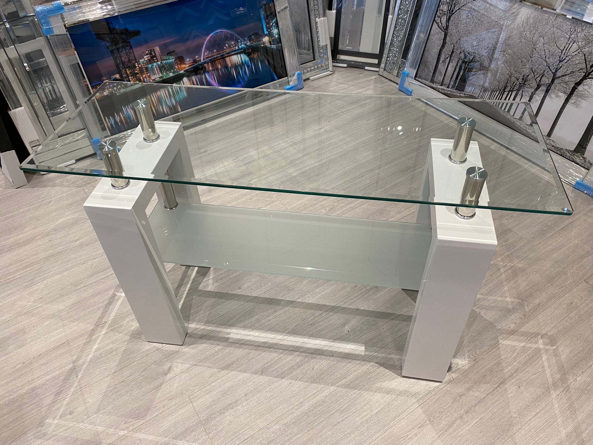 White high gloss and glass console table with a modern design on a grey floor.