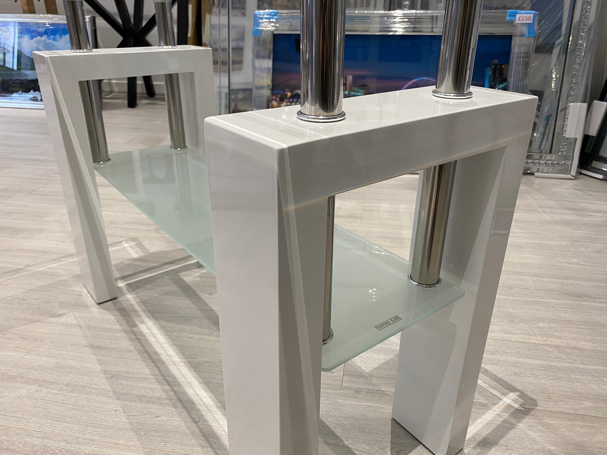 White high gloss and glass console table with a modern design on a grey floor.