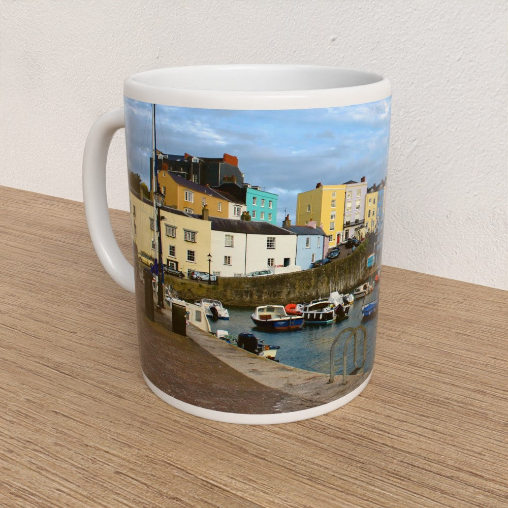 Mug with a scenic design of colourful buildings and a dock on a wooden surface.