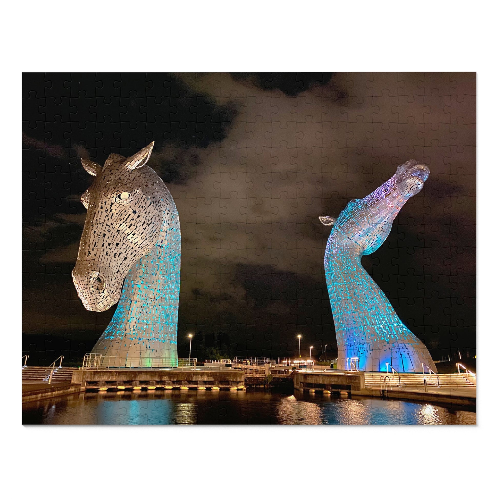 Two large horse head sculptures illuminated with blue lights against a dark sky.