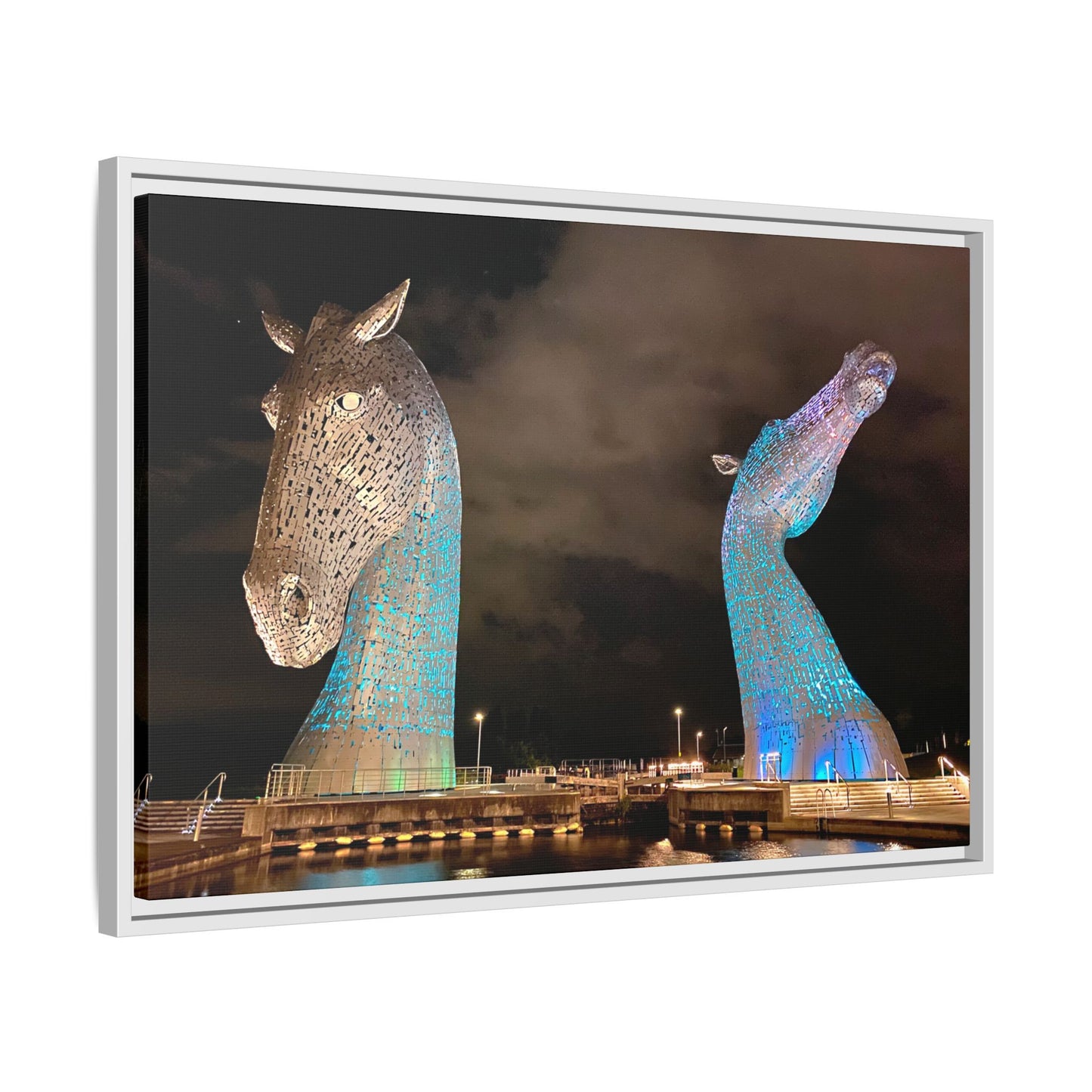 Two large horse head sculptures illuminated with blue lights against a dark sky.