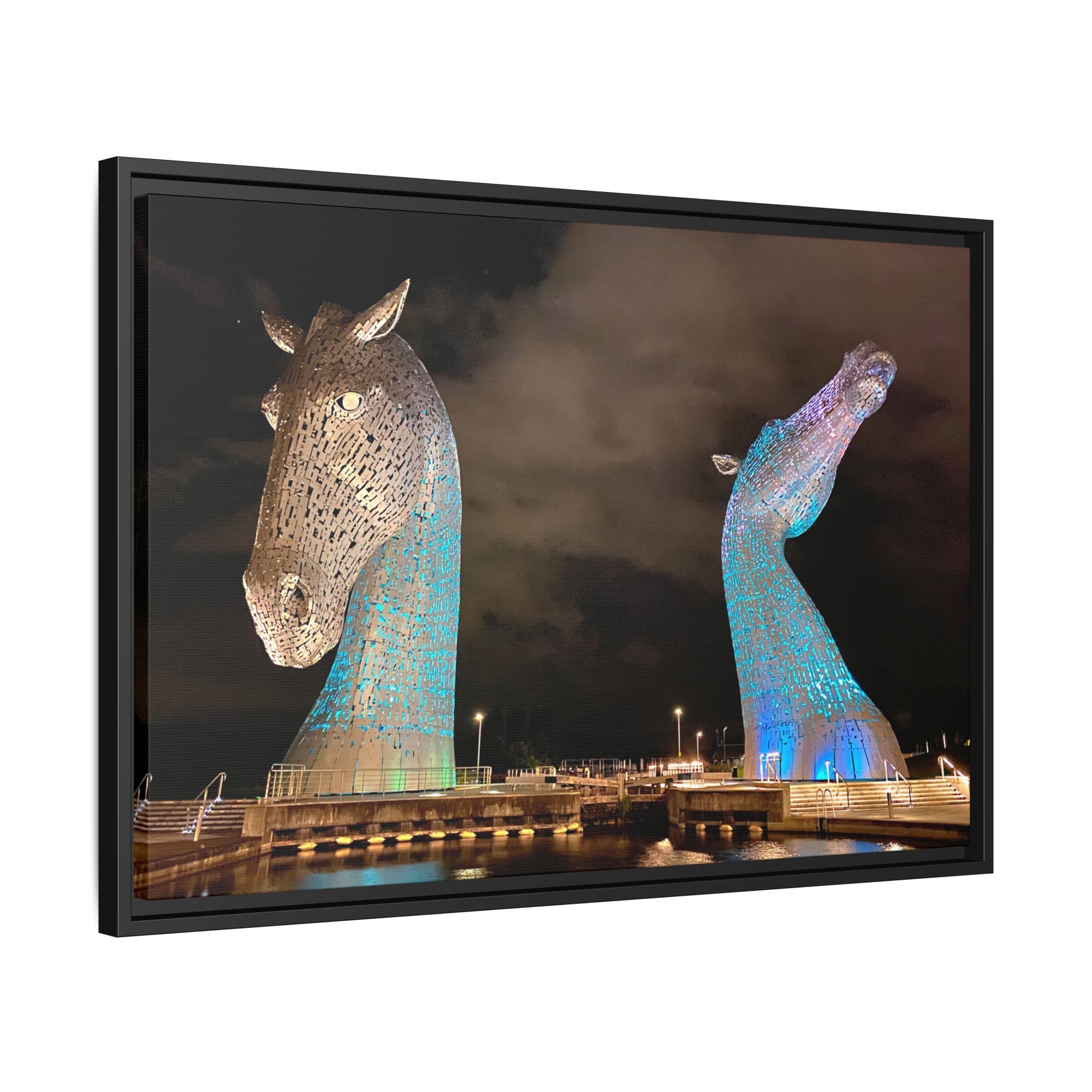 Framed artwork of two large horse head sculptures against a dark sky.