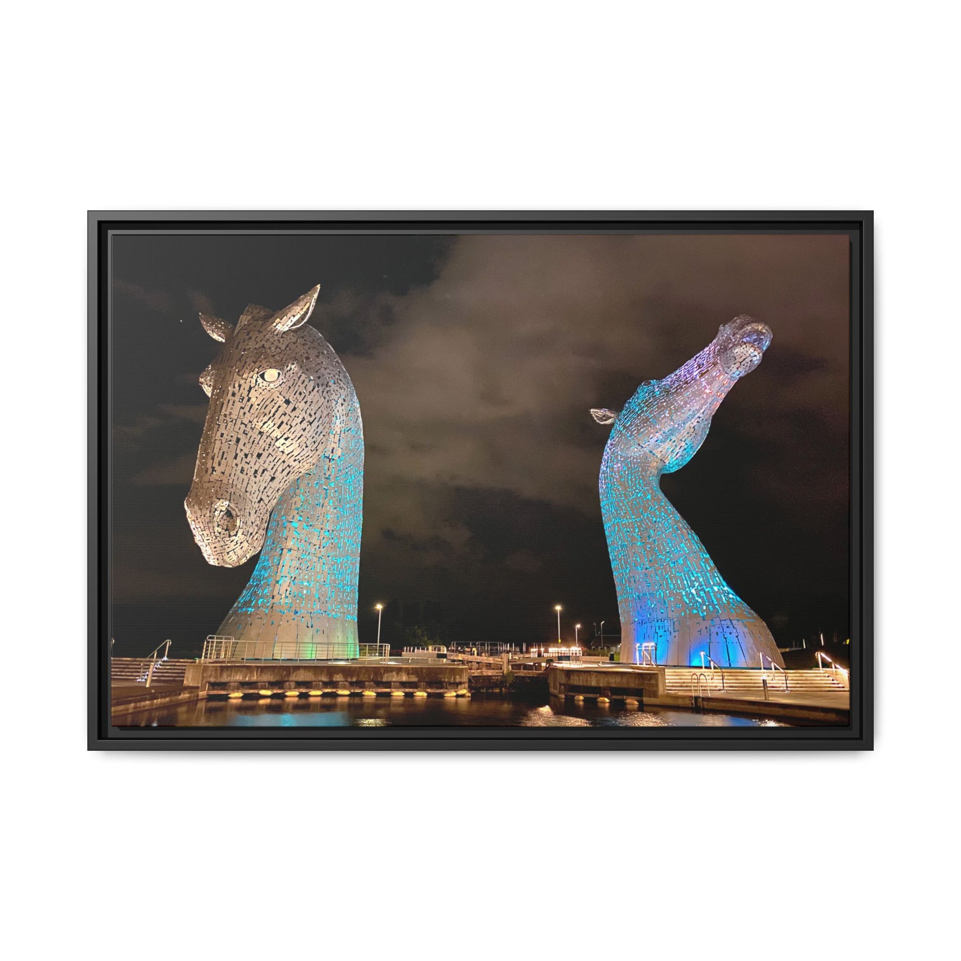 Framed artwork of two large, illuminated horse head sculptures against a dark sky.