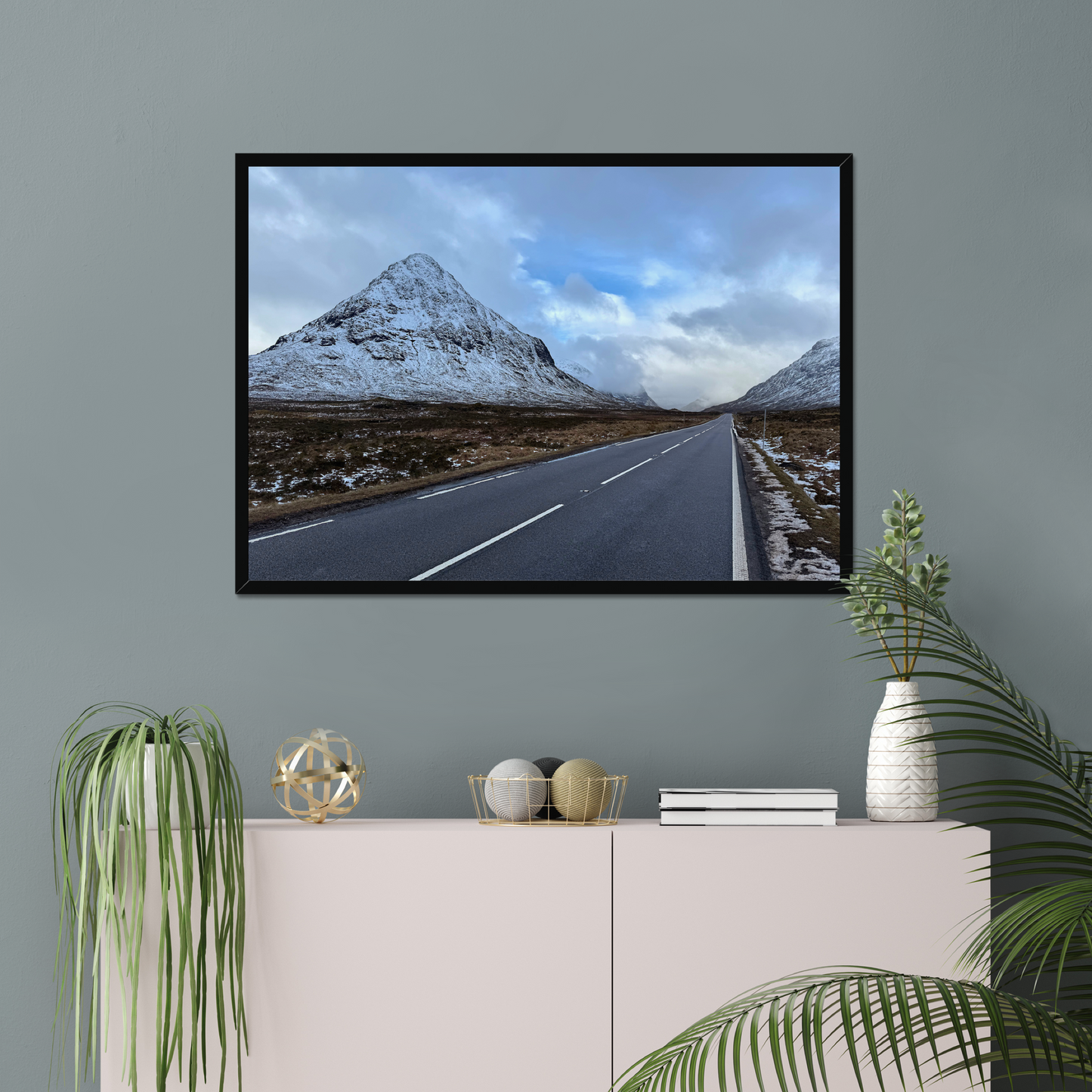 Framed photograph of a road leading towards snow-capped mountains under a cloudy sky