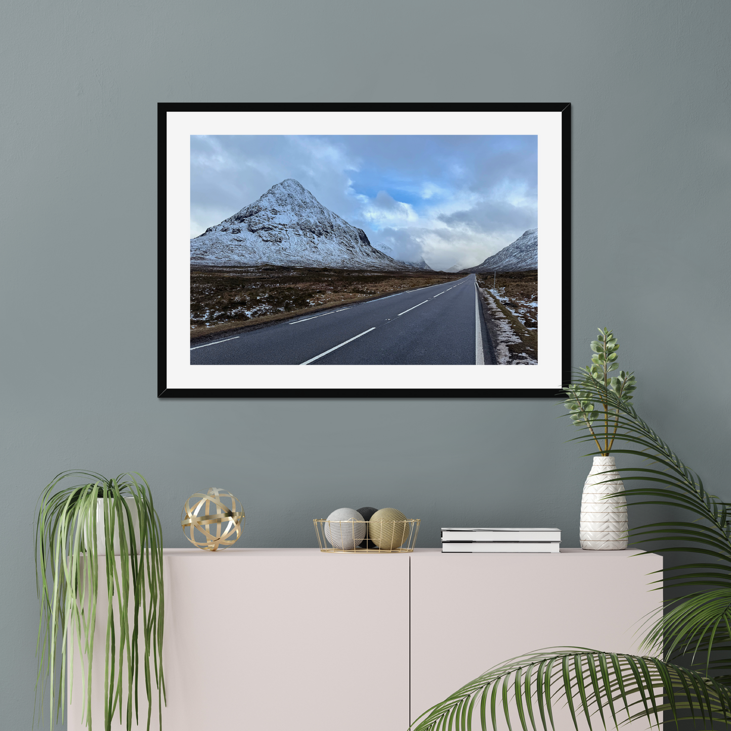 Framed photograph of a road leading towards snow-capped mountains under a cloudy sky