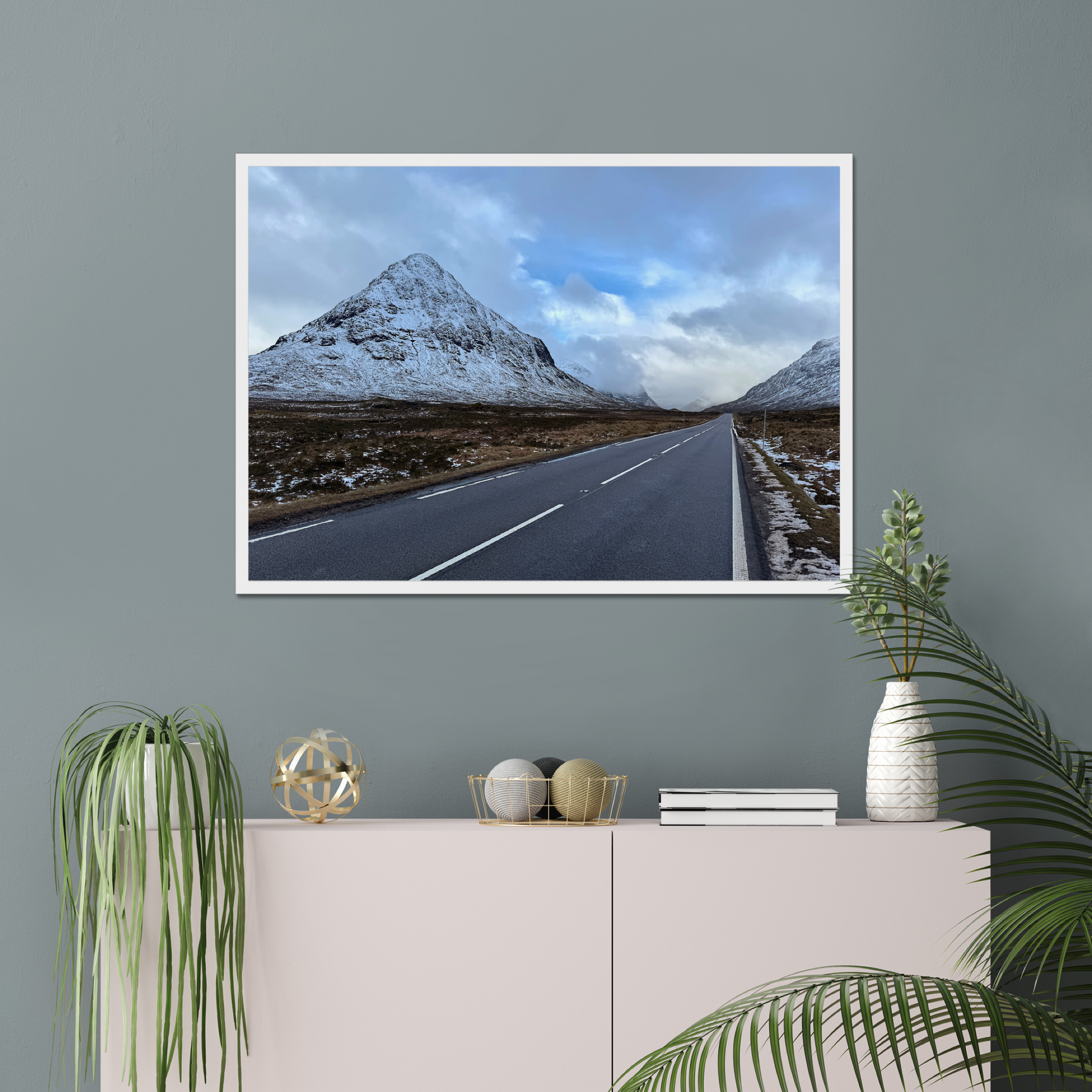 Framed photograph of a road leading towards snow-capped mountains under a cloudy sky