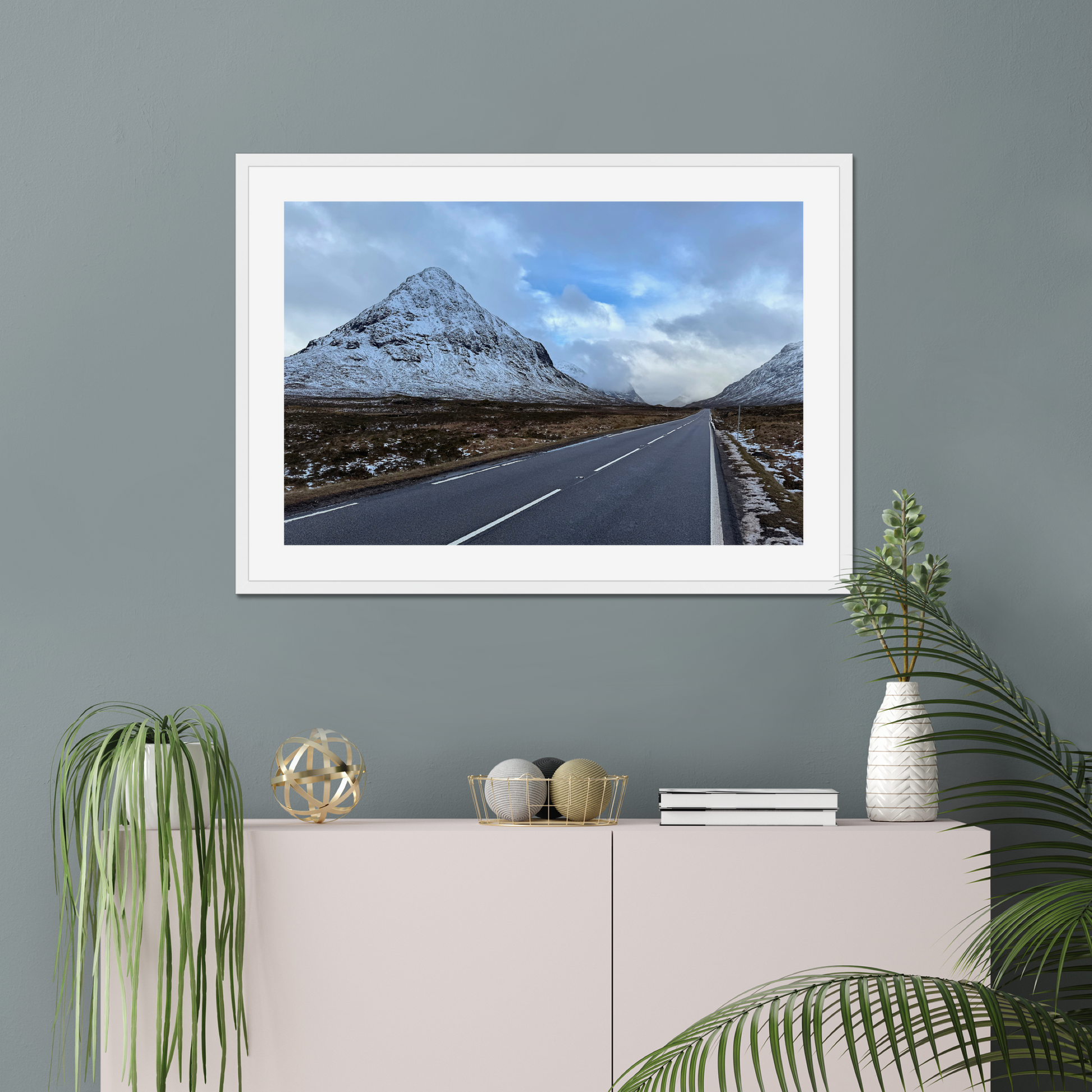 Framed photograph of a road leading towards snow-capped mountains under a cloudy sky