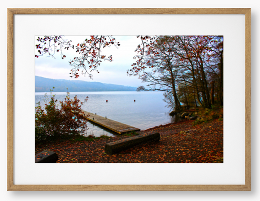 Framed Photo of a Autumn scene by a lake with a wooden jetty and trees with red leaves.