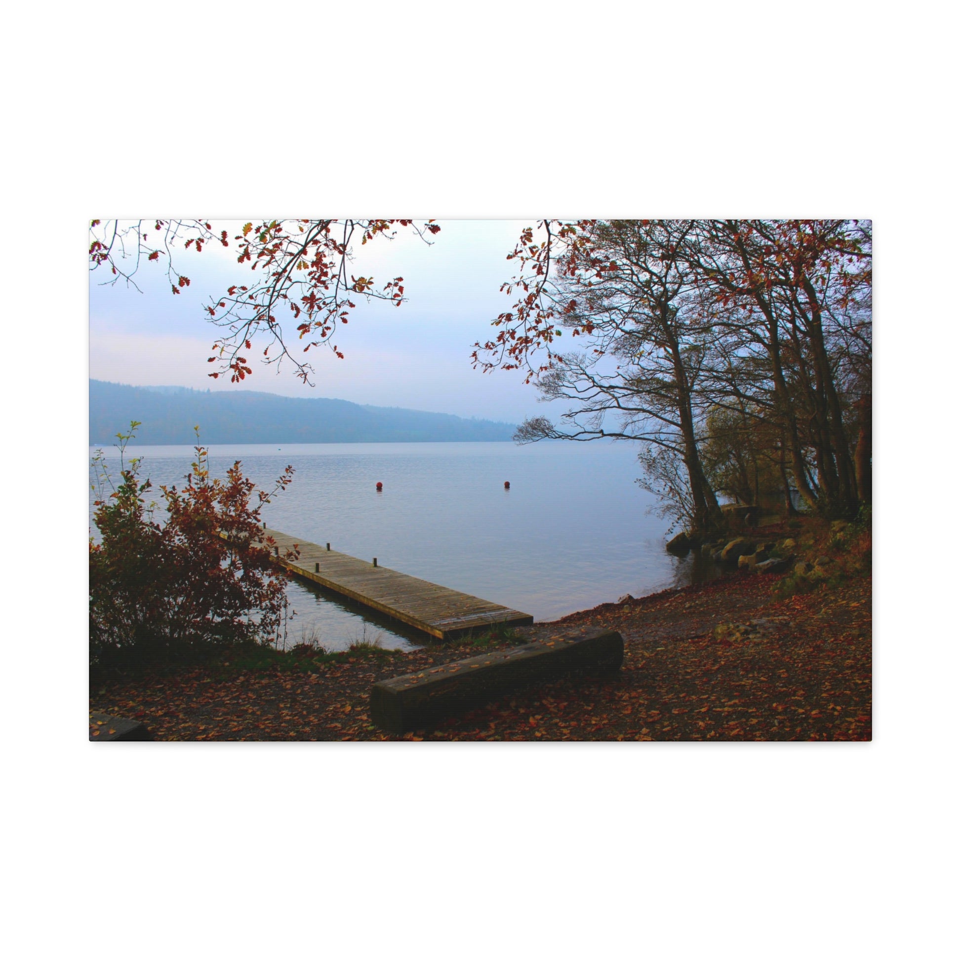 Wooden dock extending into a lake with trees and autumn foliage.