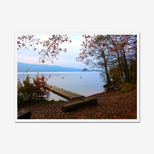 Framed photograph of a autumn scene by a lake with a wooden jetty and trees with red leaves.