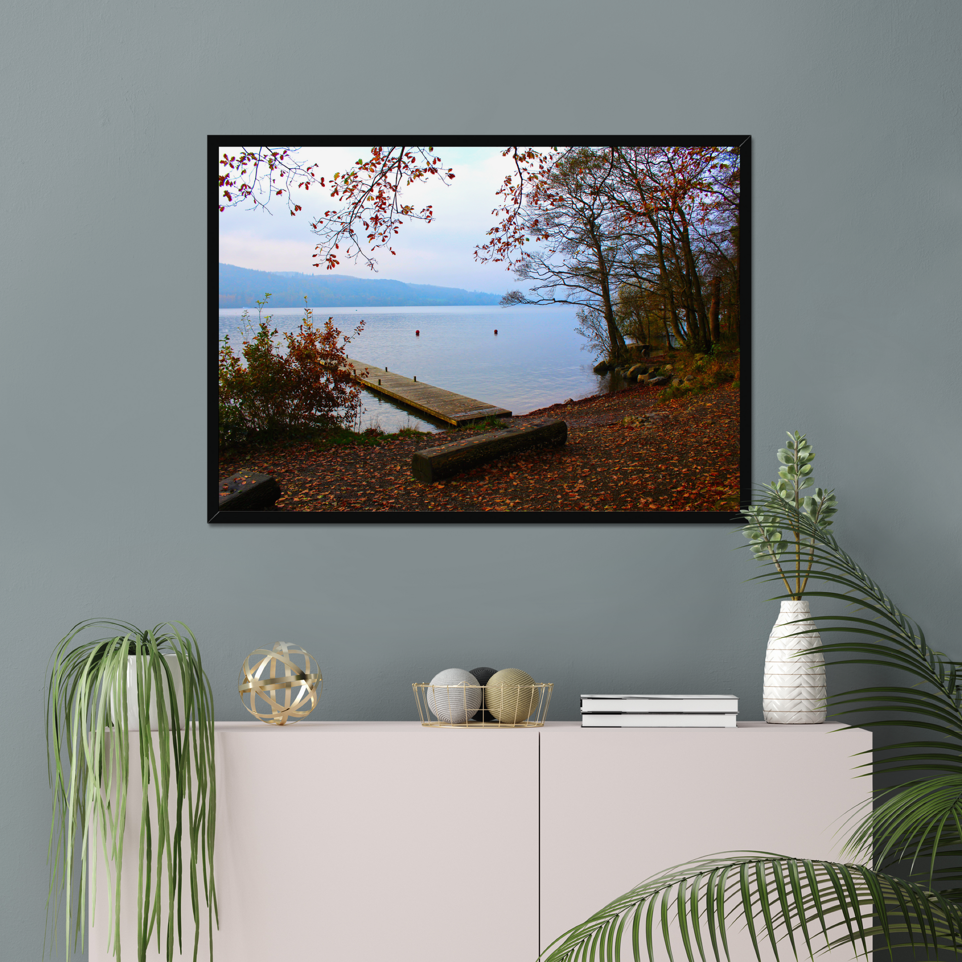 Framed photograph of a autumn scene by a lake with a wooden jetty and trees with red leaves.