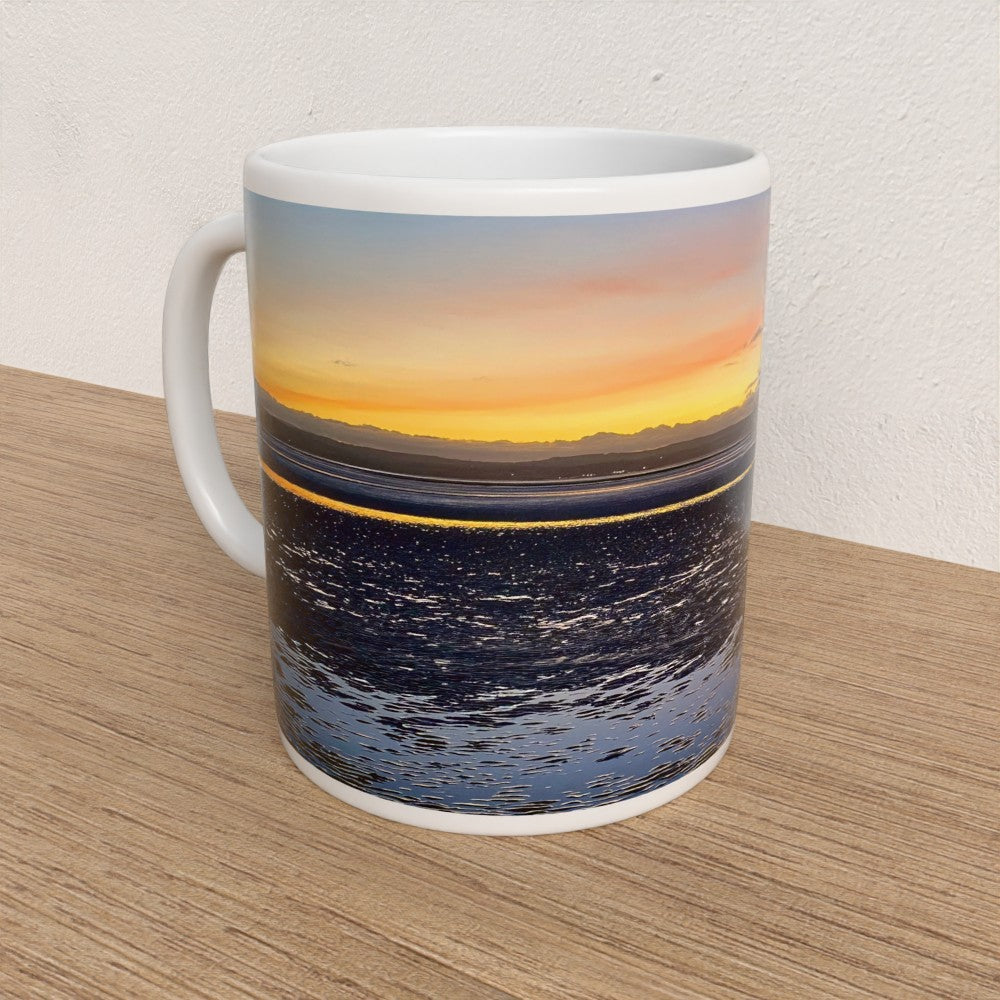 Mug with a sunset over water design on a wooden surface