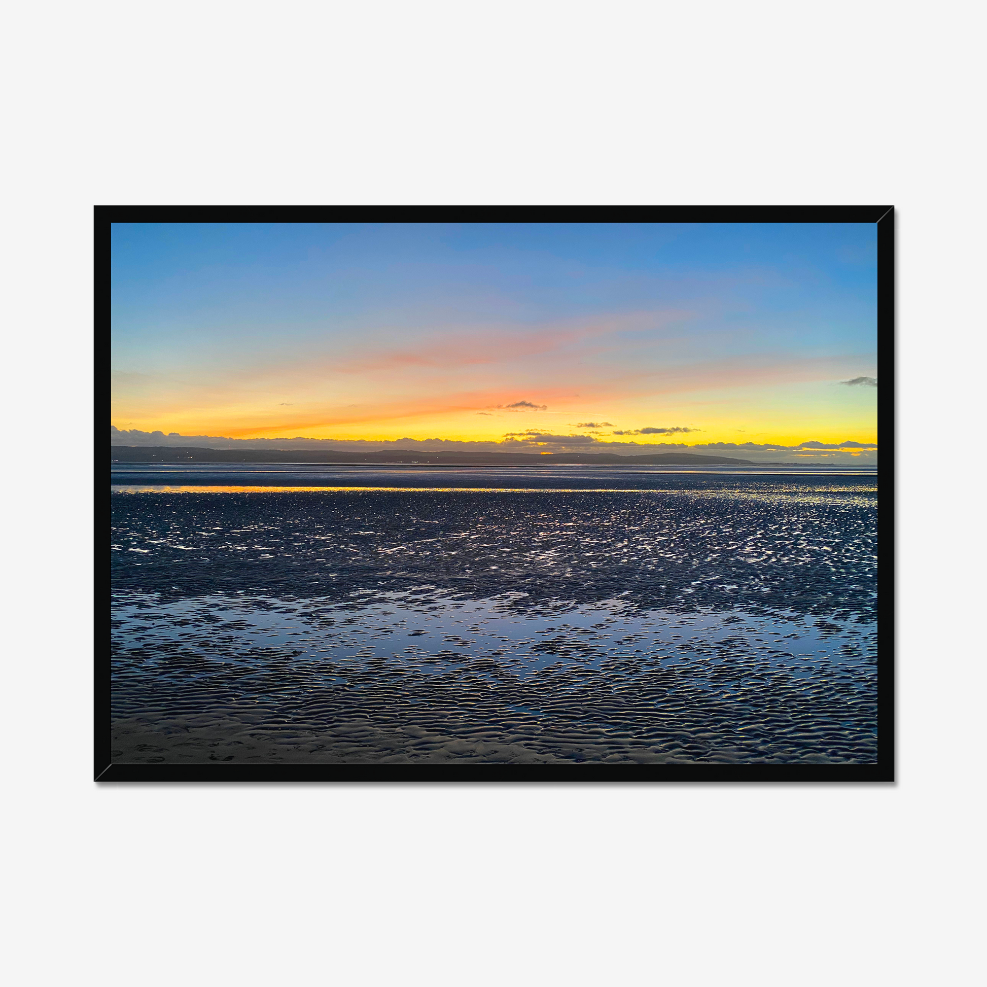 Framed photograph of a sunset over a calm body of water with a colourful sky.