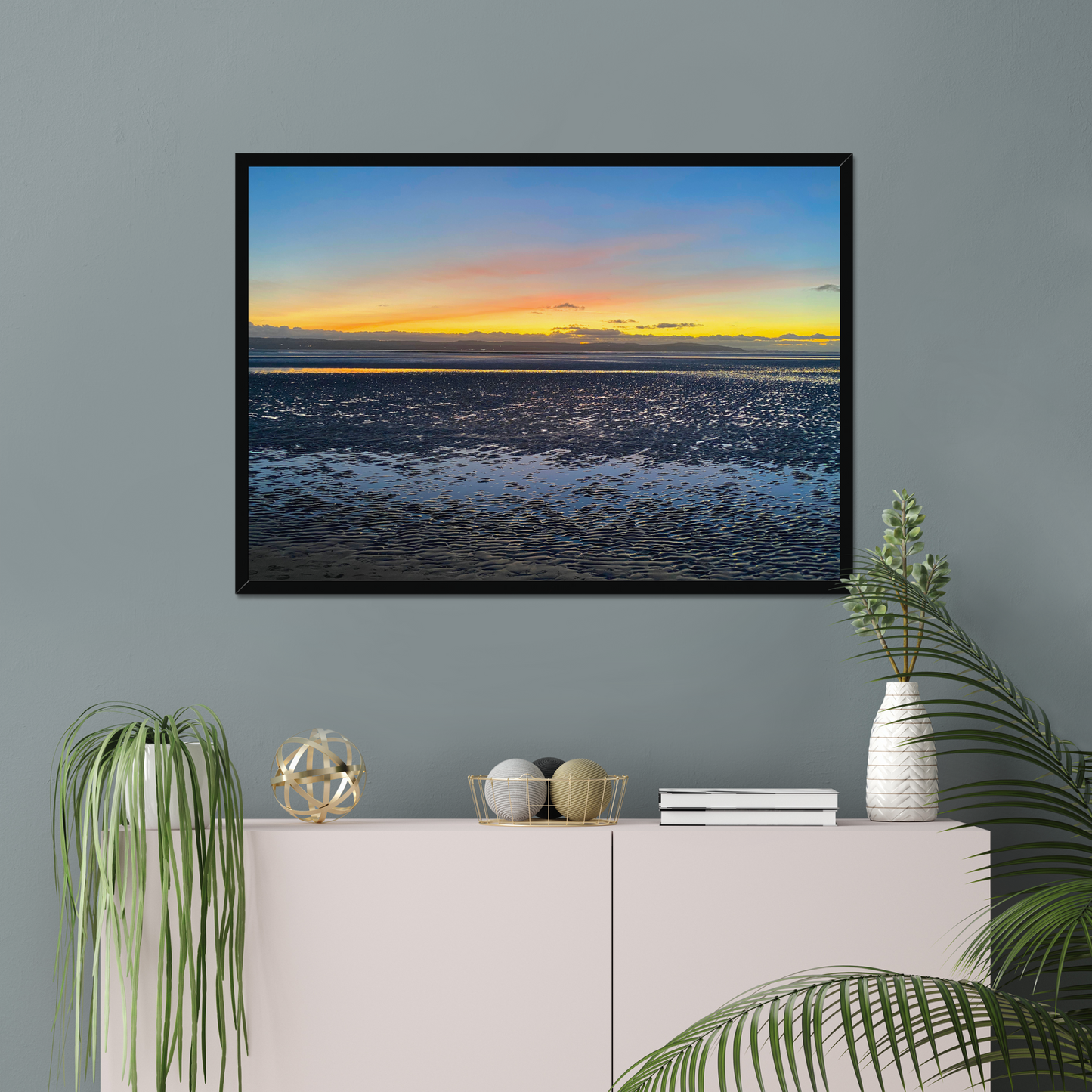 Framed photograph of a sunset over a calm body of water with a colourful sky.